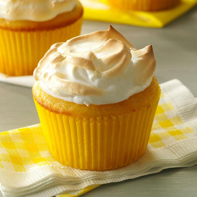 a cheery bright yellow muffin on an equally colourful napkin showing off a dollop of torched meringue in place of icing