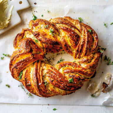a twisted, round pastry with a golden cheesy crunchy top, sprinkled with herbs and bacon bits